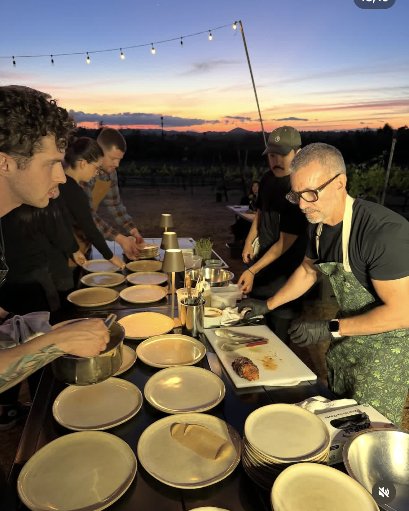 Dean and Pablo plating at sunset under string lights at a pop-up dinner