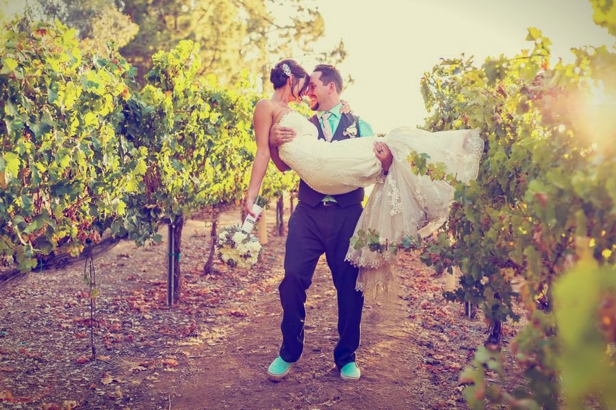 A groom carrying his bride on the vineyard path