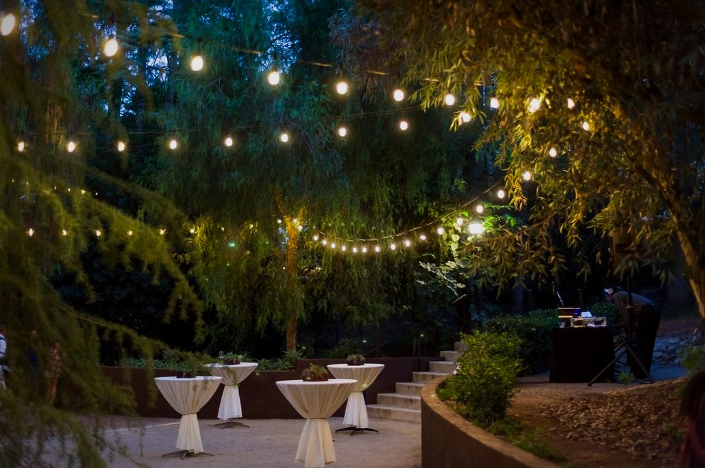 A wedding reception under string lights at dusk on the Hill Top patio