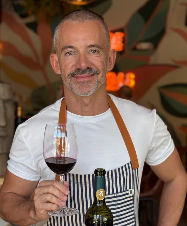 Chef Pablo Ranea holding a glass of red wine at Hill Top Winery